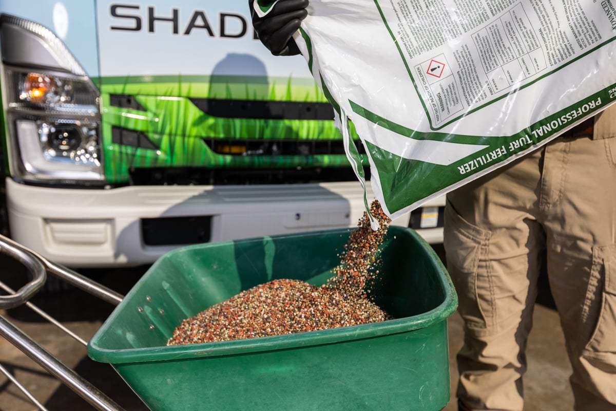 miarka pełna brązowych granulek obornika obok taśmy mierniczej na ziemi