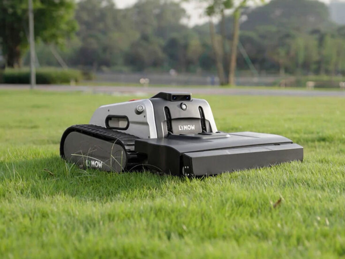 Różne modele robotów koszących ustawione na trawie w ogrodzie
