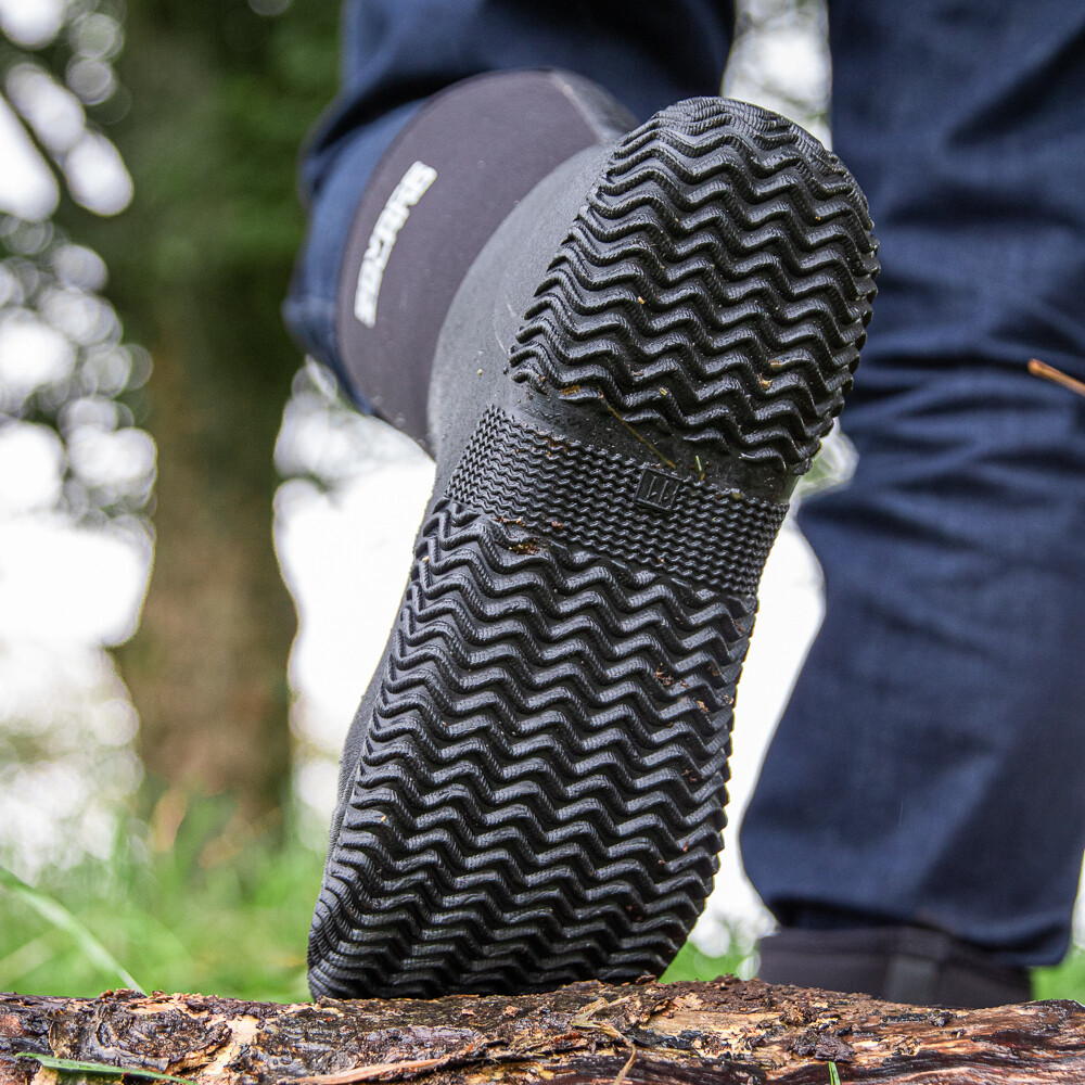 żółte gumowe kalosze pokryte błotem stojące obok mokrej grządki warzywnej