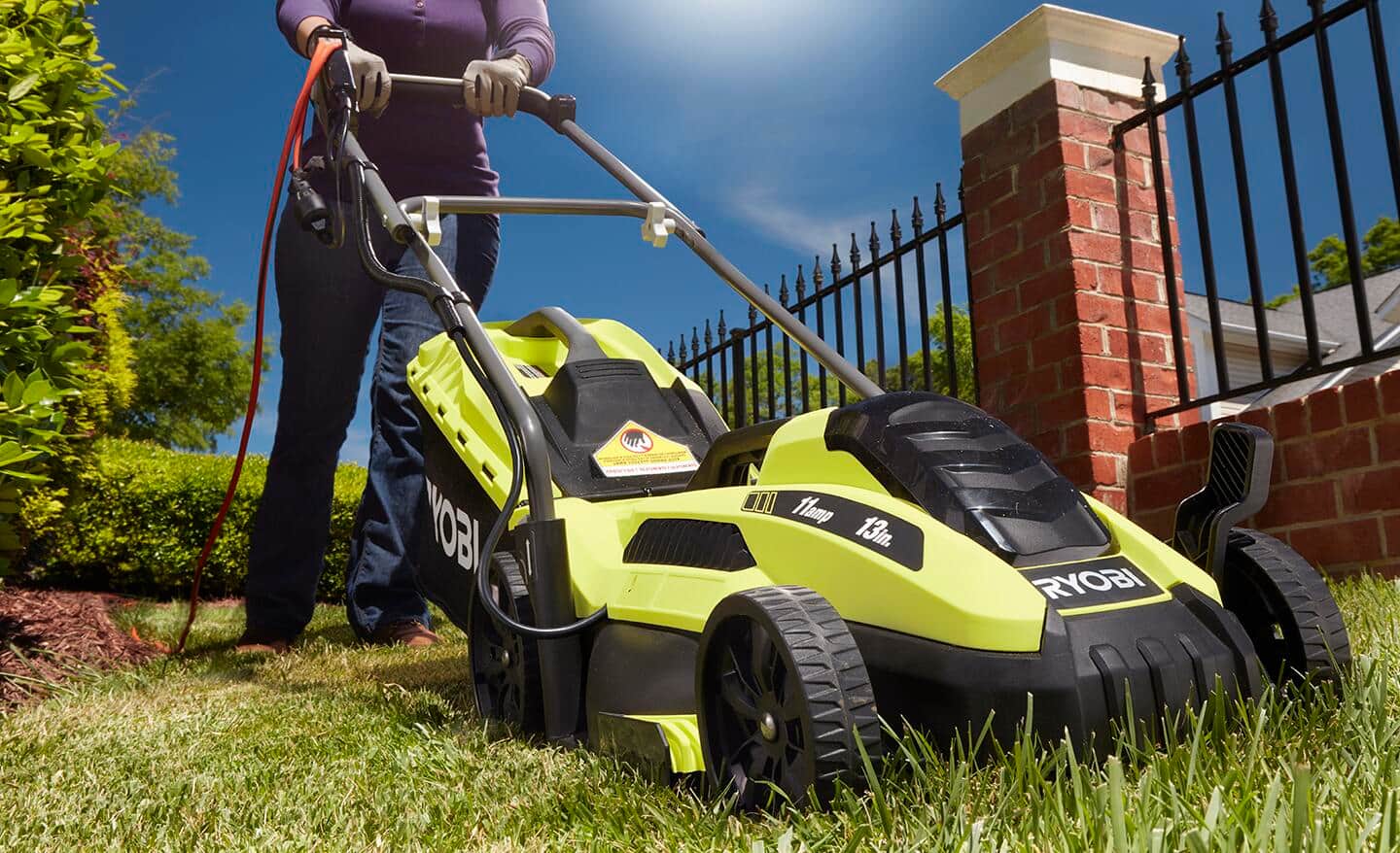 Mężczyzna ciągnie linkę rozrusznika kosiarki spalinowej na trawniku