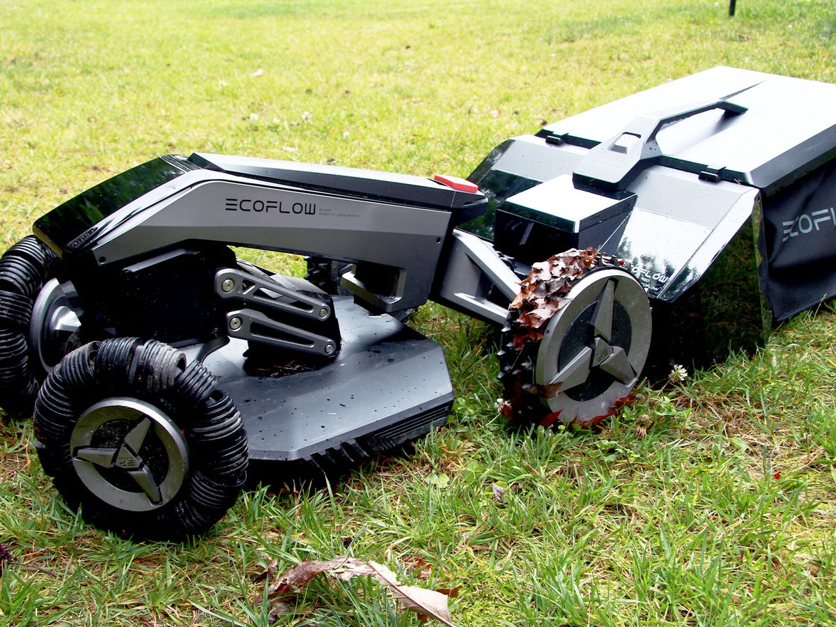 Robot koszący trawę na wzgórzowatym terenie z kwiatami w tle