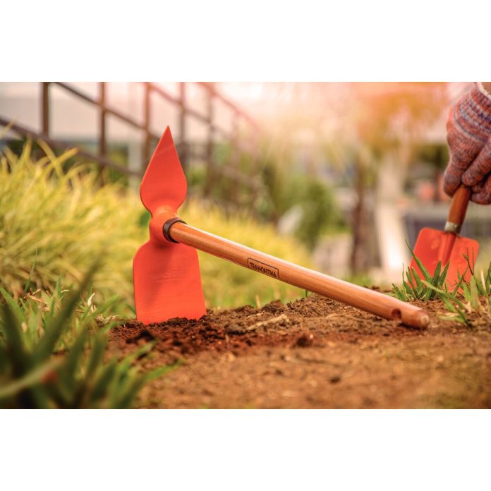 ogrodnik w słomianym kapeluszu pielący chwasty motyką w warzywniku