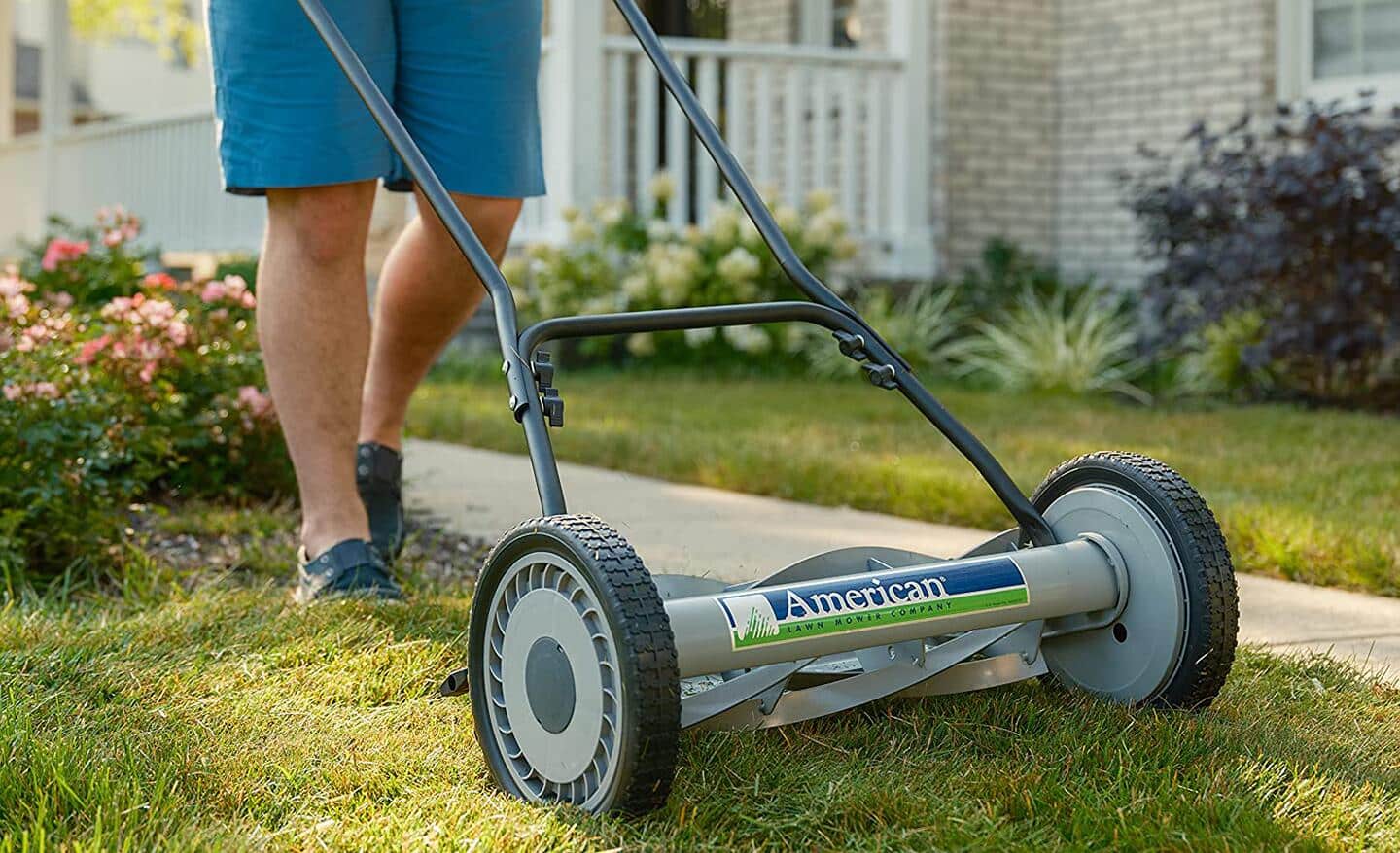 Kobieta czyści trawę spod kosiarki spalinowej po koszeniu